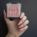Hand holding box of shiny pink coffin press on nails