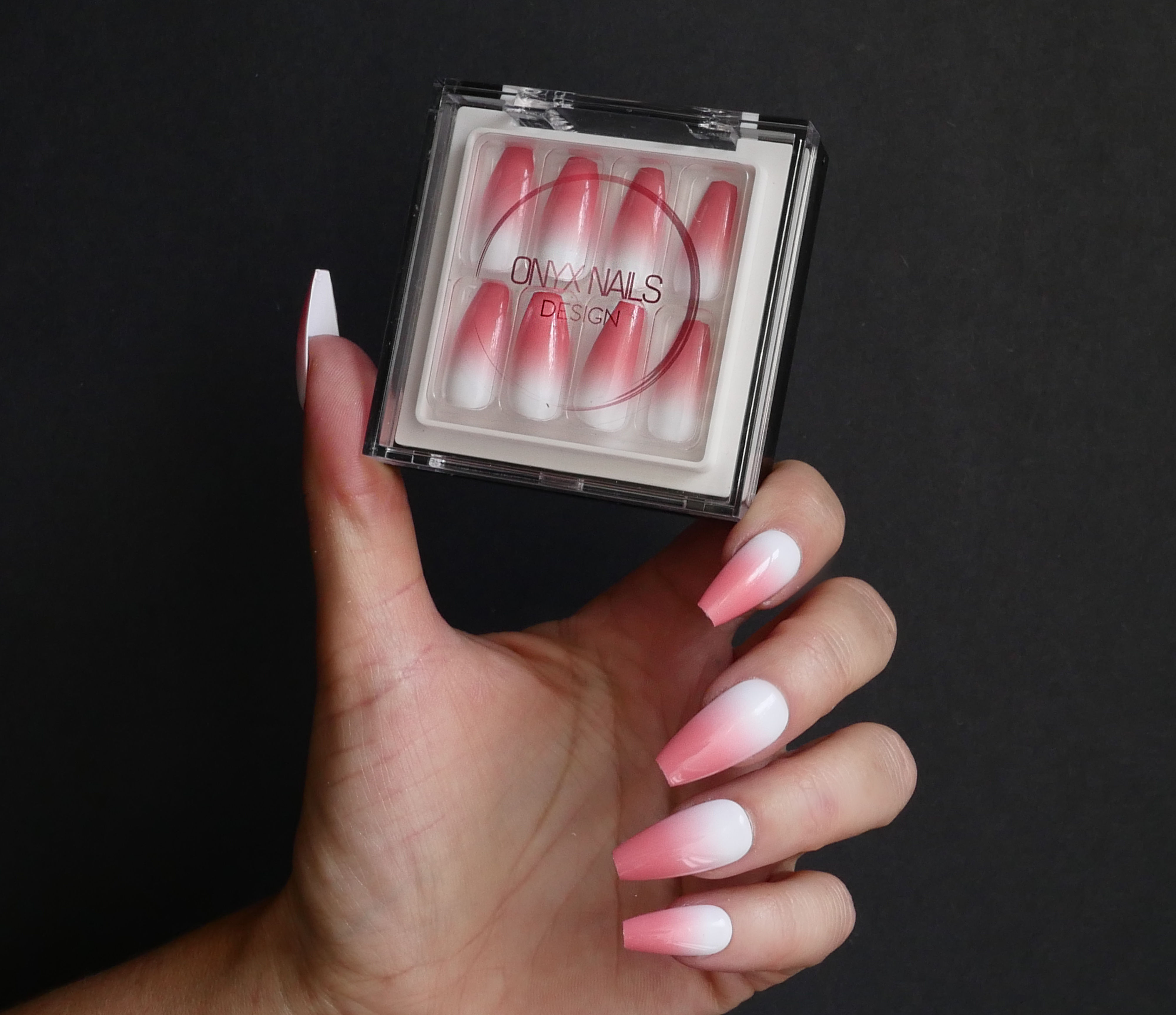 Hand holding box of pink and white fade ballerina nails