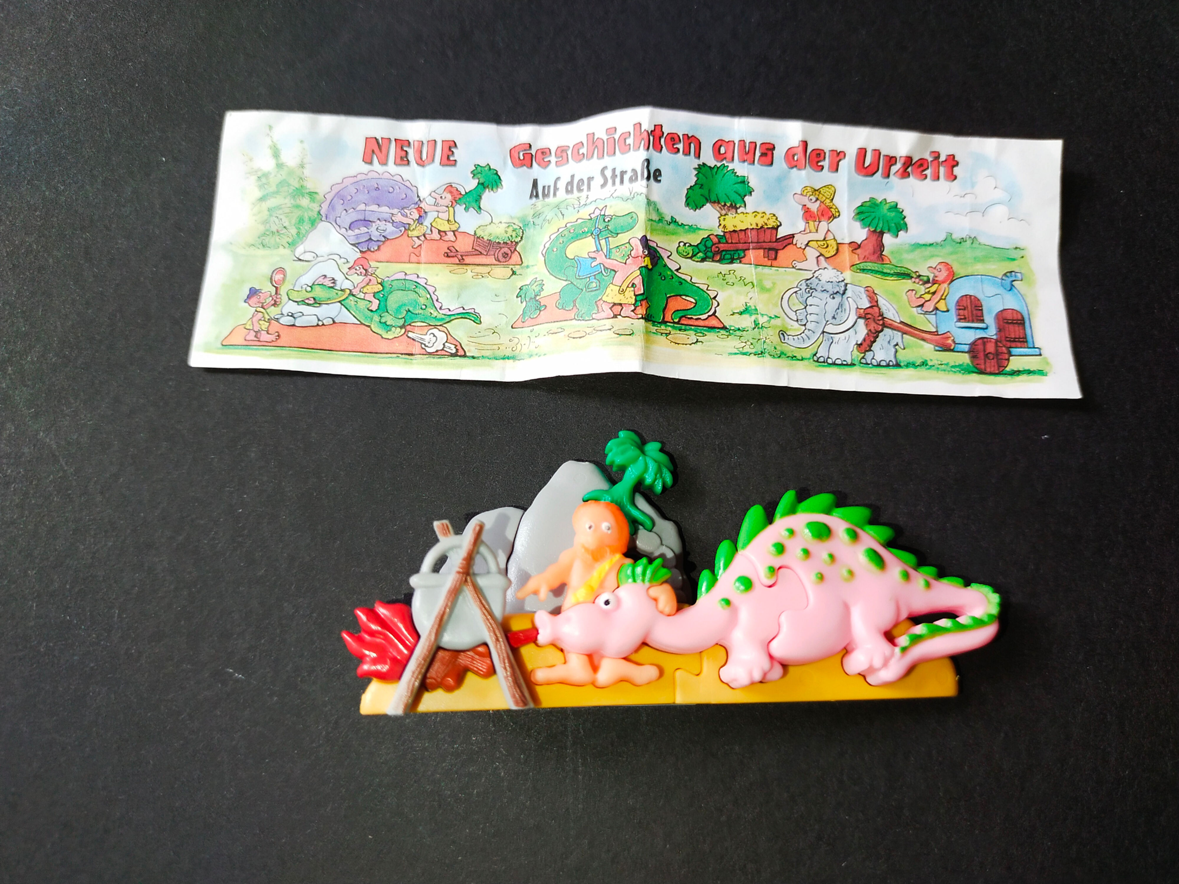 Dinosauří figurka s obrázkem: "Neue Geschichten aus der Urzeit"