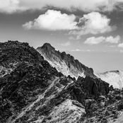 Cumbres montañosas rocosas bajo un cielo con nubes.