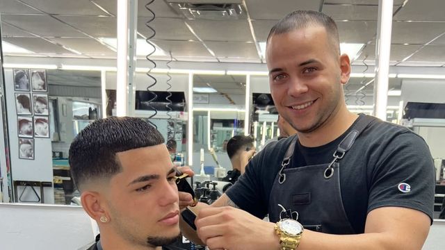 Elier finishing a client haircut