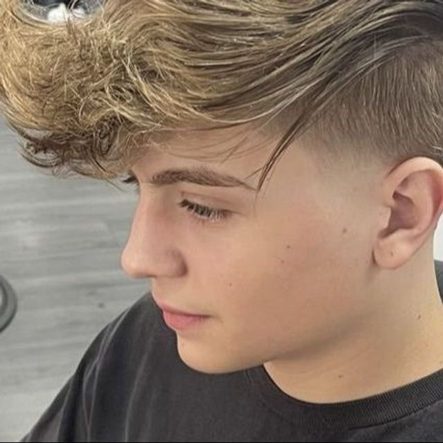 Blond client with a clean skin fade and styled side-swept haircut