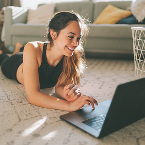 Woman laying on the floor, smiling at her laptop