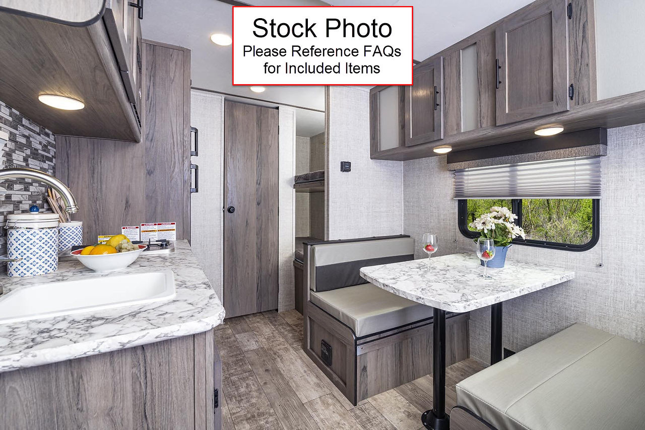 RV kitchen and dining area with marble countertops and gray wood cabinetry
