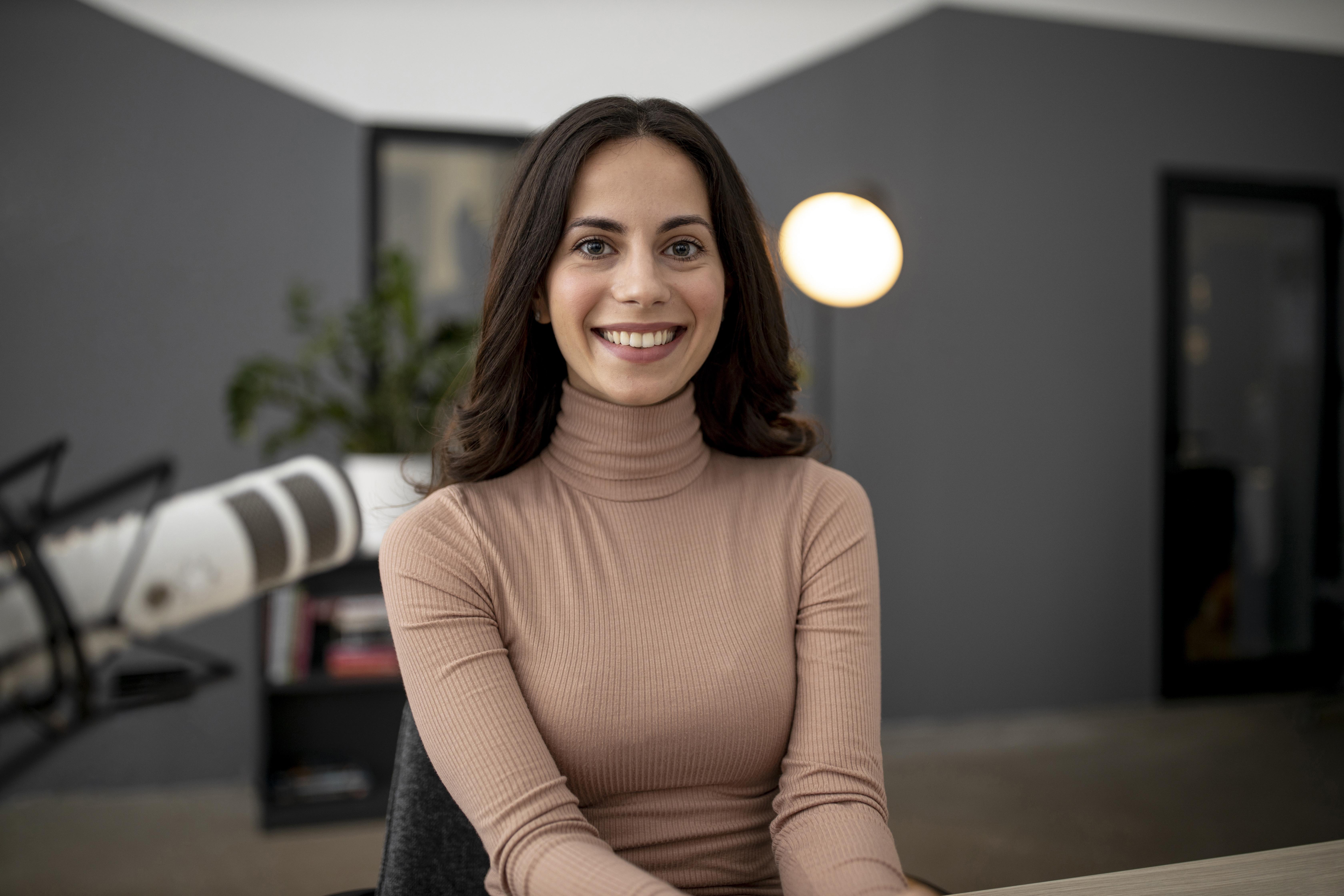 vista-frontal-de-uma-mulher-sorridente-em-um-estudio-de-radio-com-microfone.jpg