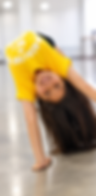 Young girl in yellow shirt performing a backbend in class