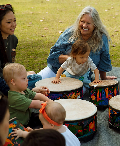 Grandmother with grandson doing a drum activity together in an outdoor family music class