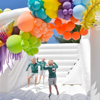 Three boys bouncing on a white bounce house for a fun summer things party