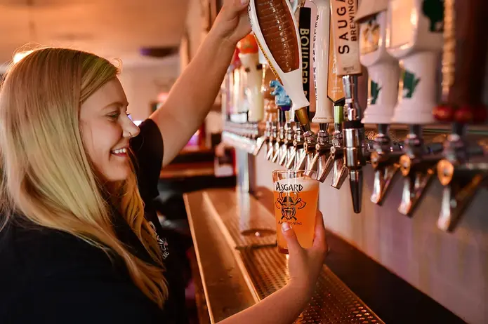 Woman pouring a pint of Asgard beer from the tap at Asgard Axe and Tap in Wisconsin Dells