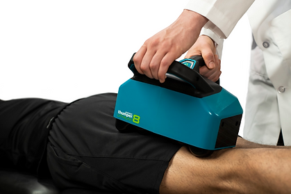 Therapist using Thumper massager on patient’s legs for pain relief.