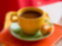Coffee cup next to a Brigadeiro that has a bite taken out of it.
