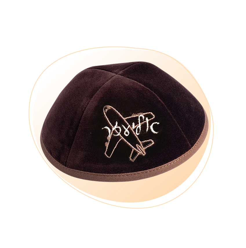 An embroidered brown yarmulke with airplane and custom name through it on the front.