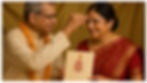 Indian Parents holding a wedding Invitation card