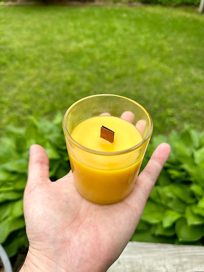 single wood wick beeswax container candle being held in a man's hand