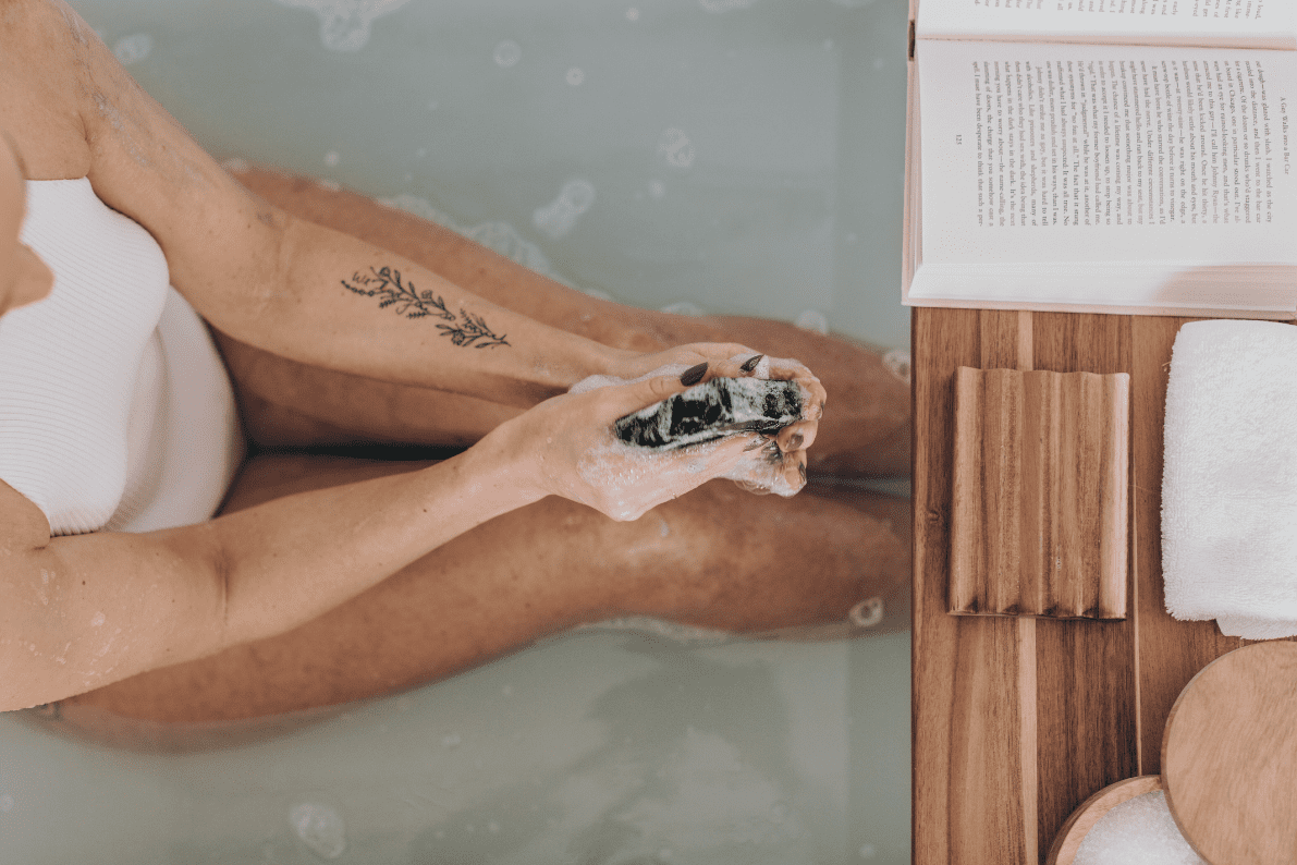 A woman taking a bath and washing off with Unplugged Essentials Knight Body Bar.