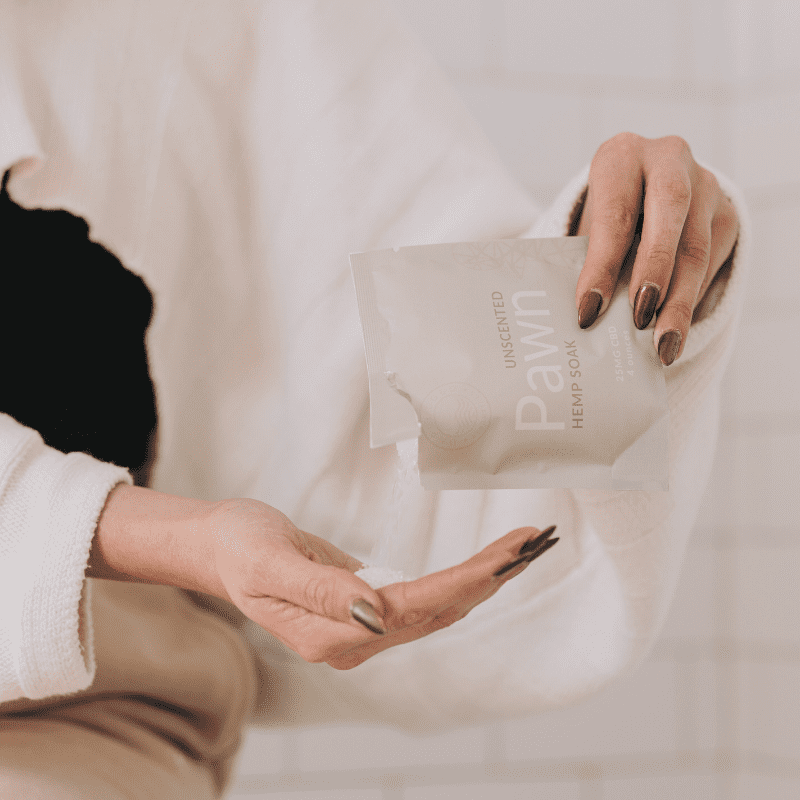 a woman unpackaging the pawn soak from Unplugged Essentials in 4 ounces.