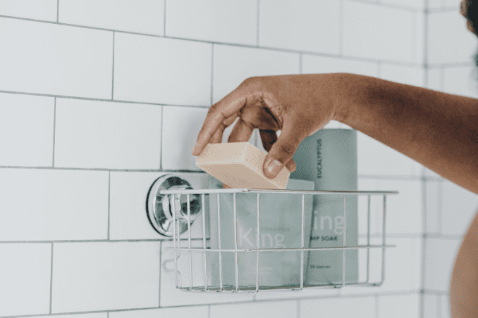 A man placing his King Body Bar into the shower caddy after use.