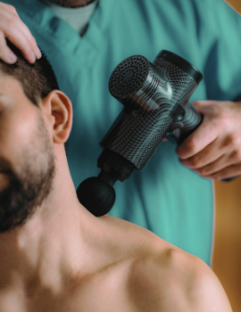 A man receiving a percussion massage to aid in post-workout muscle recovery and relaxation.