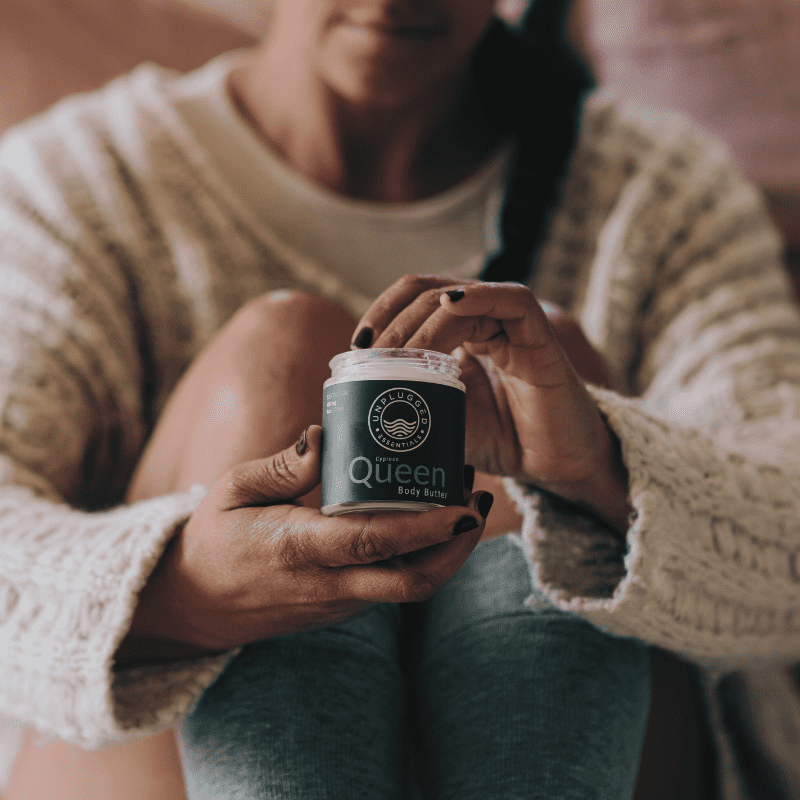 A woman holding the Queen Body Butter up after taking a bath.