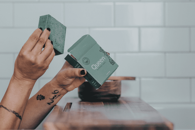 A woman unboxing Unplugged Essentials Queen Body Bar while taking a bath.