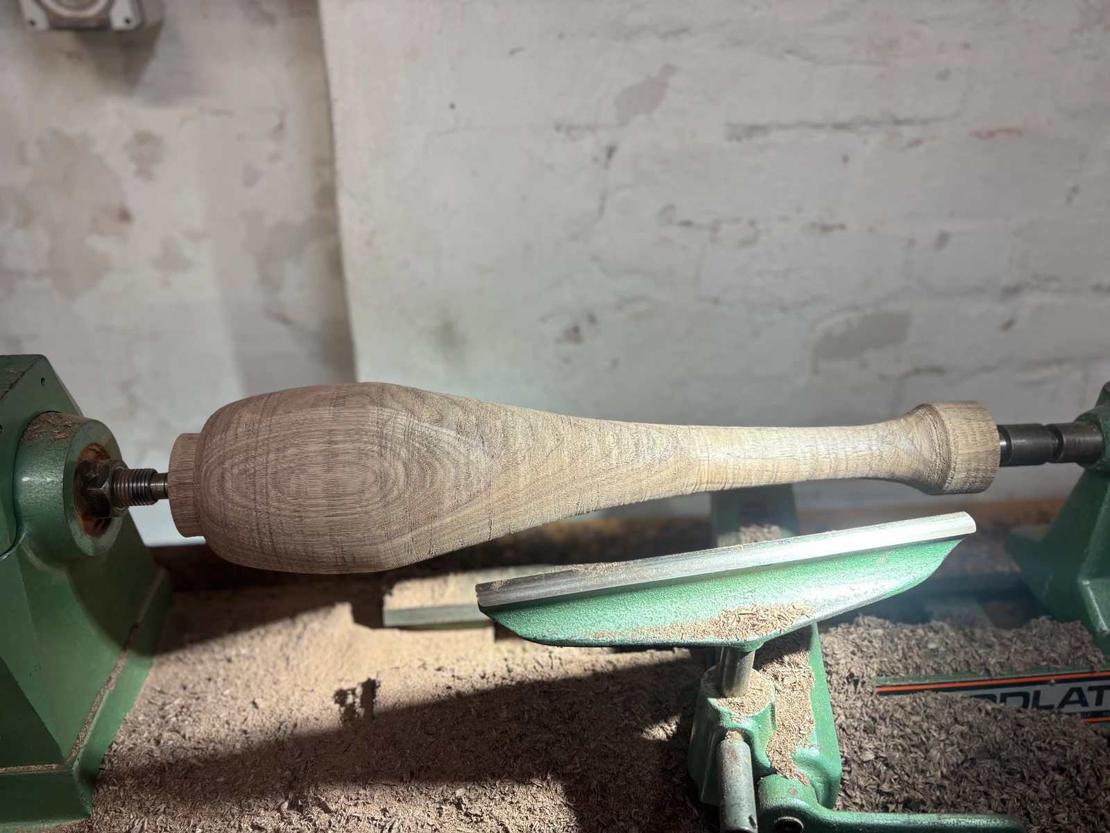 A shaped timber component mounted on a wood lathe.