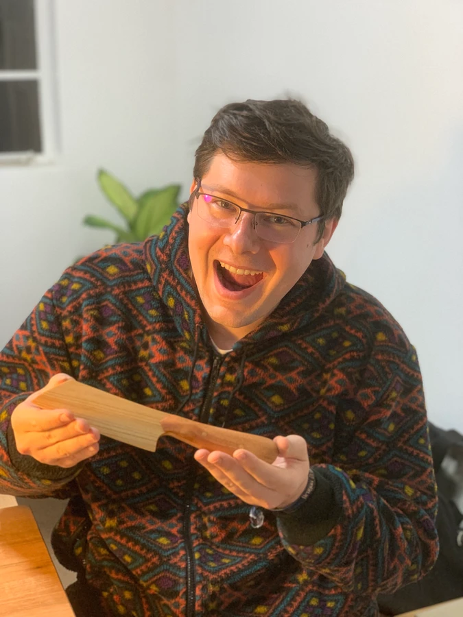 A student holding up a wooden knife in the workshop.