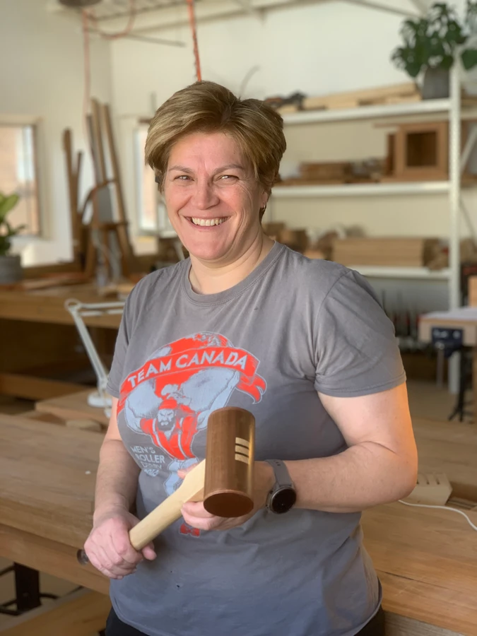 A student holding a completed wooden mallet.