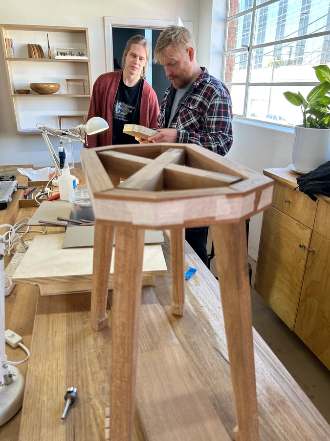 Students fitting a seat to a timber stool frame.