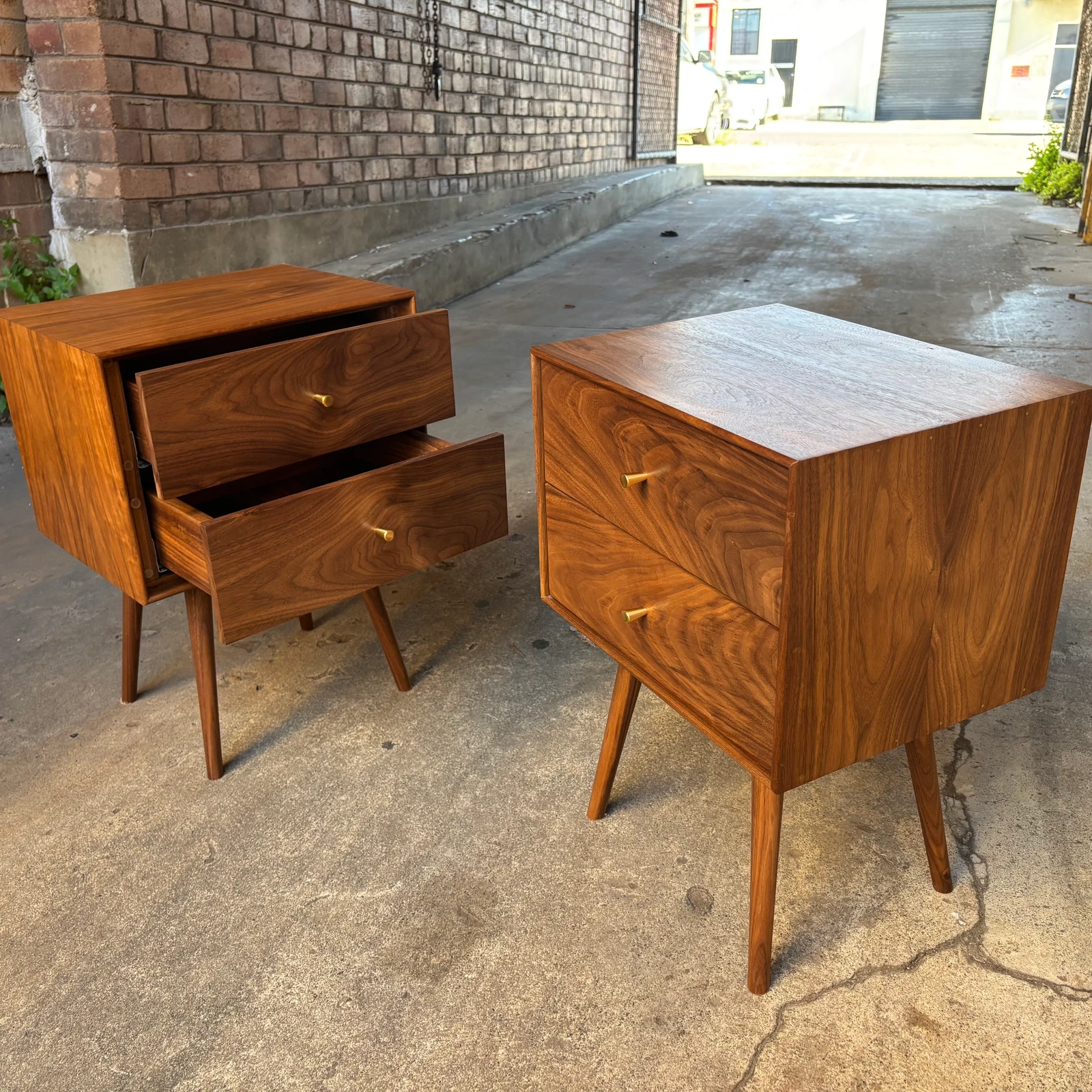 An angled view of two timber bedside cabinets with open drawers.