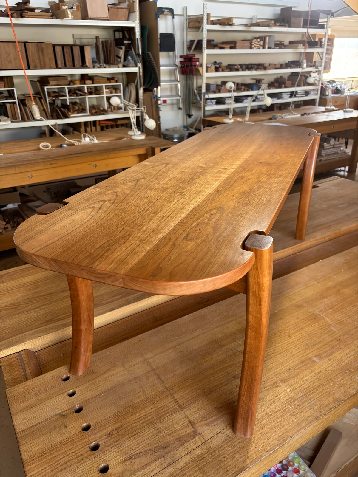 A completed timber table with a rounded end on a workbench.
