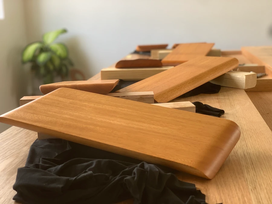 Finished timber boards and wooden knives displayed together on a bench.