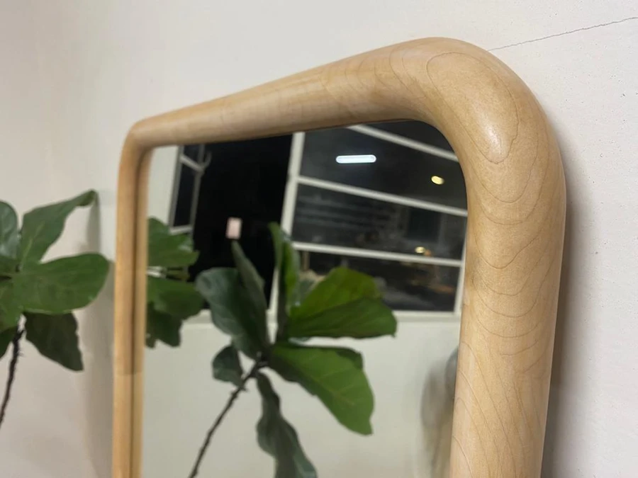 Rounded timber joinery at the corner of a mirror frame.