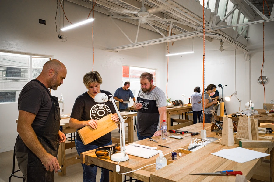A teacher and students discussing a timber board at the workbench.