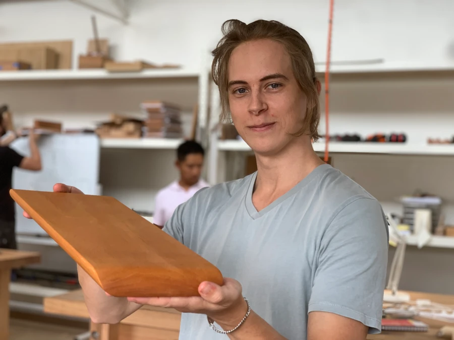 A student holding a completed timber cheese board.