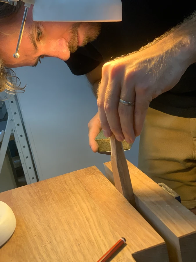 A student carving a wooden knife held in a bench vice.