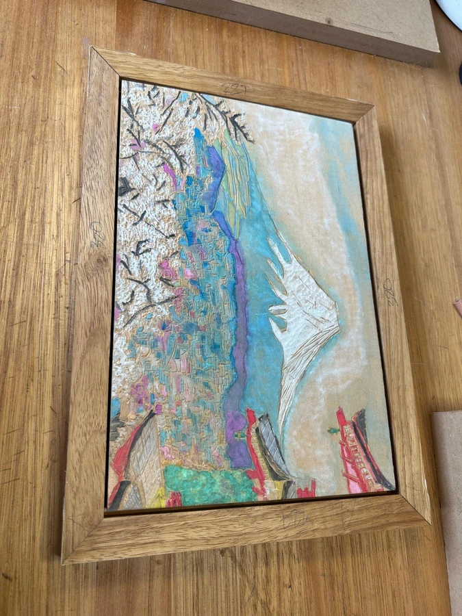 A completed timber picture frame surrounding a colourful artwork.