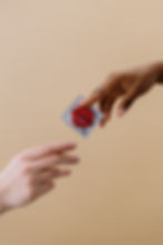 One person handing another person a condom.