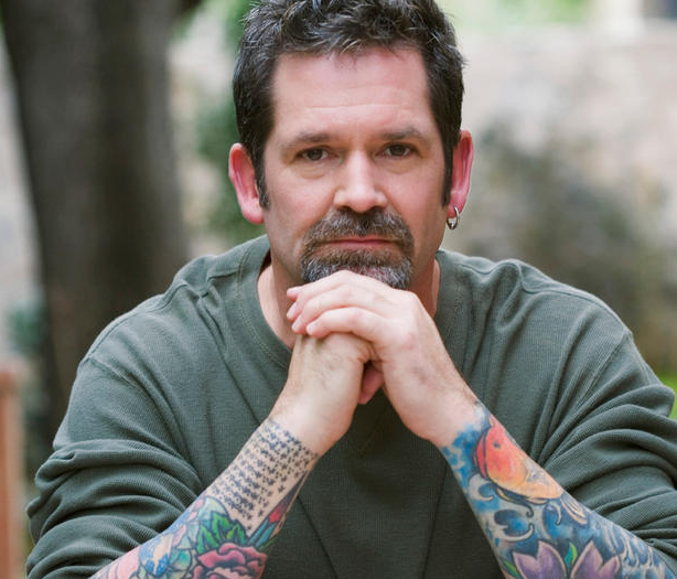 A man with tattoos looking pensive