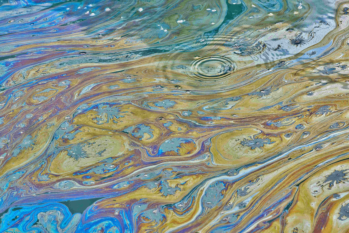 Hydrocarbon pollution on the surface of water creating an iridescent oil sheen. Oils and hydrocarbons reduce oxygen transfer, block sunlight, and can be harmful to aquatic ecosystems.