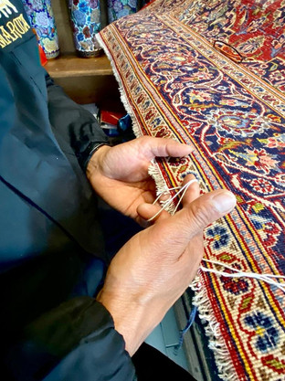 particolare delle mani di un artigiano che restaurano un tappeto persiano