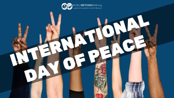 Hands of diverse people make peace signs against a blue background. Text reads "International Day of Peace" with a peaceful mood.
