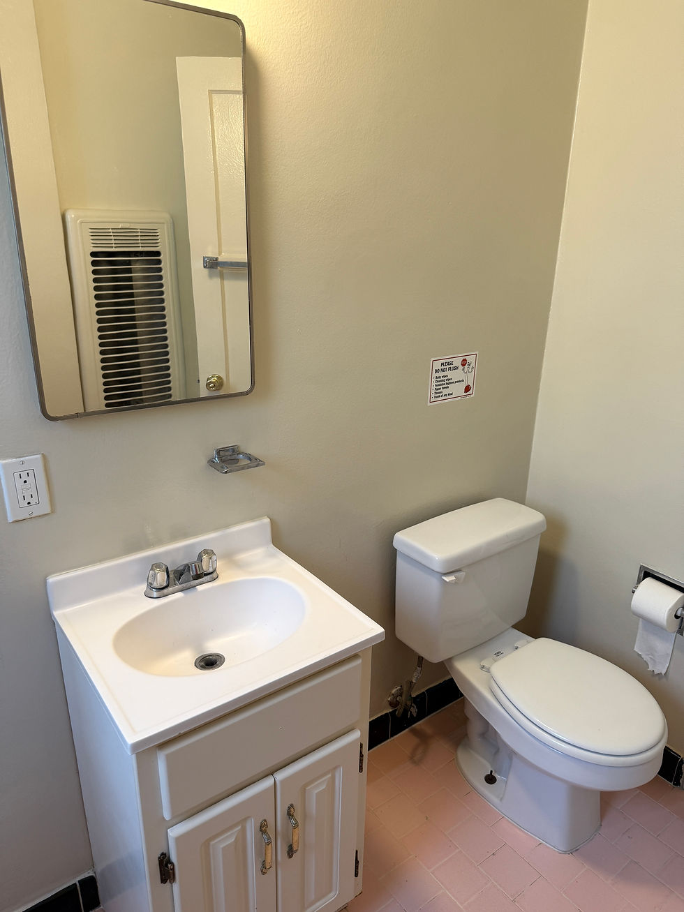 Simple and clean bathroom view featuring a sink, toilet, and heater, as seen from the doorway.