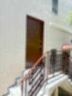 Apartment front door with a metallic railing and stairs leading up to the entrance.