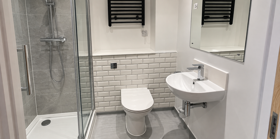 Finished bathroom with toilet, basin, grey tiled walls and heated towel rail