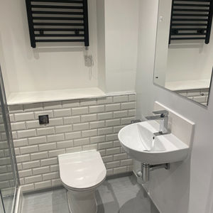 Finished bathroom refurbishment with toilet, basin, tiled walls and heated towel rail