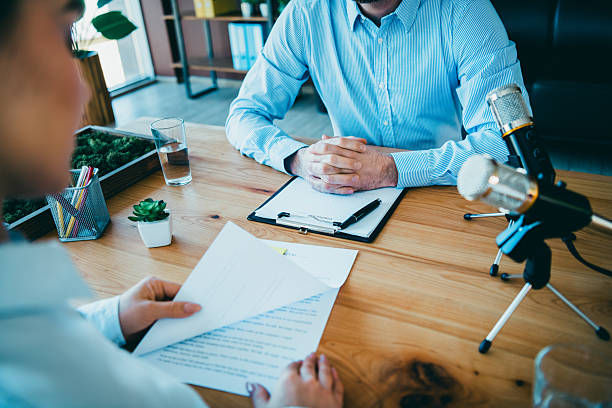 Two foreign men discussing business and reviewing documents across a desk (an entrepreneur consulting a specialist on Business Manager Visa requirements and business plans)