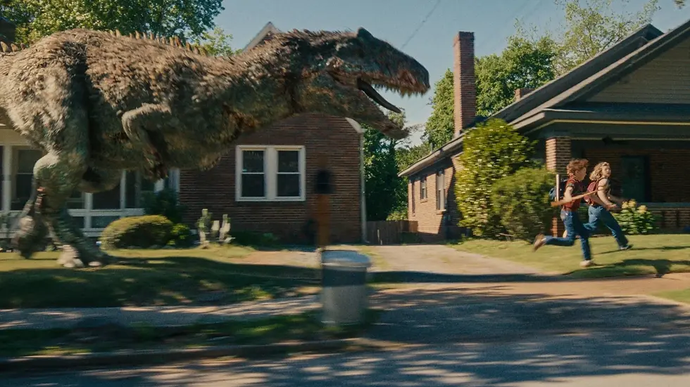 Dinossauro gigante ruge enquanto duas crianças correm em frente a casas suburbanas ensolaradas.