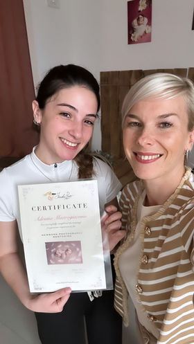 Masha e Adriana sorridenti con certificato di mentoring in fotografia newborn nello studio