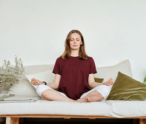 Ženska na sedežni garnituri izvaja sprostitvene tehnike za zmanjšanje tesnobe in izboljšanje počutja z vodnimi posnetki meditacije in hipnoze