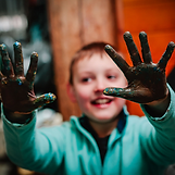 Een van de kinderen heeft zijn handen lekker vies gemaakt met modder en verf tijdens een creatieve opdracht
